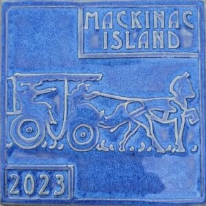 A blue tile with a picture of a horse and carriage.