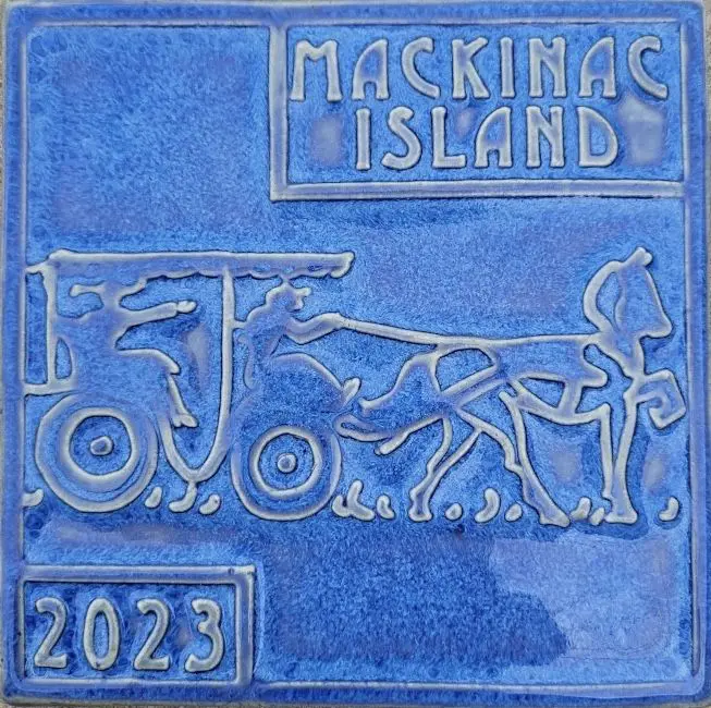 A blue tile with a picture of a horse and carriage.
